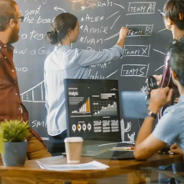 A team works together at a chalkboard