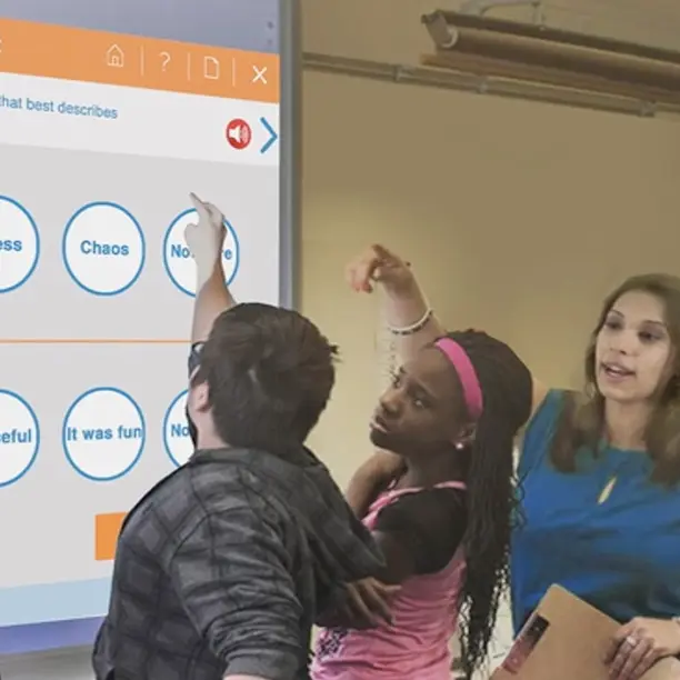 A teaher and her students discuss learning material while looking at a projector screen