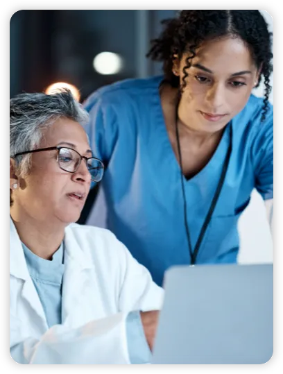 A nurse and a doctor converse over a computer